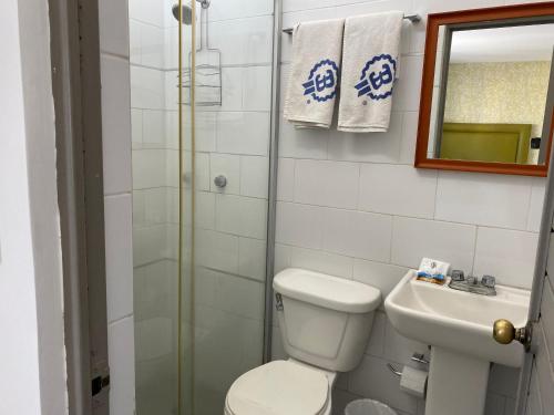 a bathroom with a toilet and a sink and a mirror at Hotel Suites Regina in Veracruz