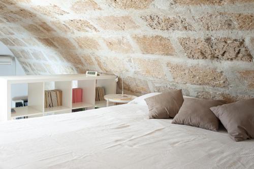 アルゲーロにあるLa Casina Apartmentの白いベッドとレンガの壁が備わるベッドルーム1室が備わります。