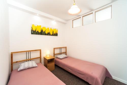 2 Betten befinden sich in einem Zimmer mit weißen Wänden. in der Unterkunft Apartamenty Dobranoc - Wawer in Warschau
