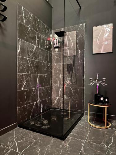 y baño con ducha y paredes de mármol negro. en Loveroom de luxe - Thème 50 nuances de grey maison privative spa insolite, en Douchy-les-Mines