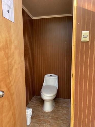 a bathroom with a white toilet in a wooden wall at CaminAndes Hostal in San Pedro de Atacama
