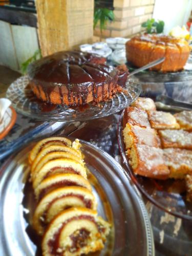 a bunch of different types of cakes and pastries on plates at Pousada Icthus in Cabo Frio