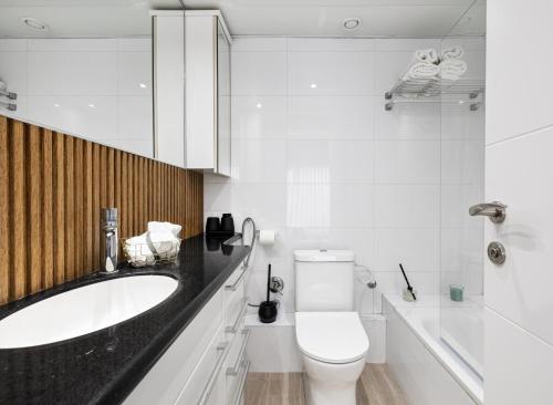 een witte badkamer met een wastafel en een toilet bij Beach Front Dream Penthouse - pool & gym & parking in Herzliyya B