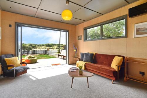 a living room with a couch and a tv at Beachfront Bach - Christchurch Holiday Homes in Christchurch