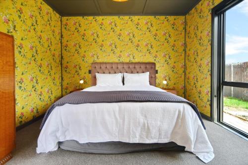 a bedroom with a bed with yellow floral wallpaper at Beachfront Bach - Christchurch Holiday Homes in Christchurch