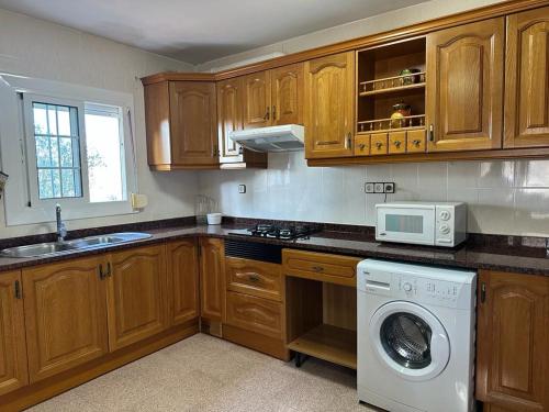 eine Küche mit Holzschränken und einer Waschmaschine in der Unterkunft Apartamento Can Giru in Tordera