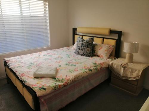 a bedroom with a bed with a floral comforter at Melbourne Lakes warm house in Melbourne