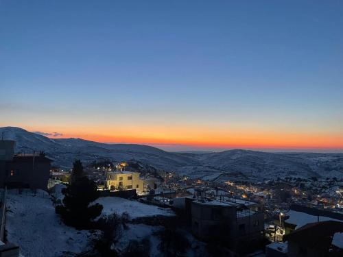 Blick auf eine Stadt im Schnee bei Sonnenuntergang in der Unterkunft ארואד סוויטס Arwad suites in Madschdal Schams