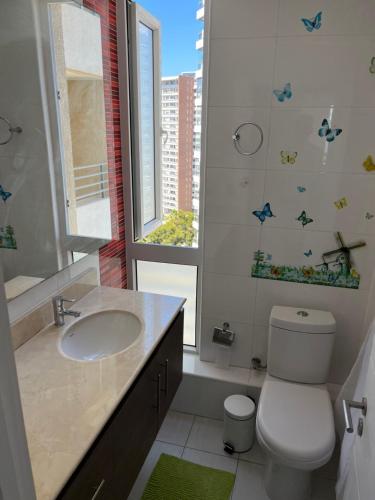 uma casa de banho com um lavatório, um WC e uma janela. em Cómodo, relajante e ideal em Concón