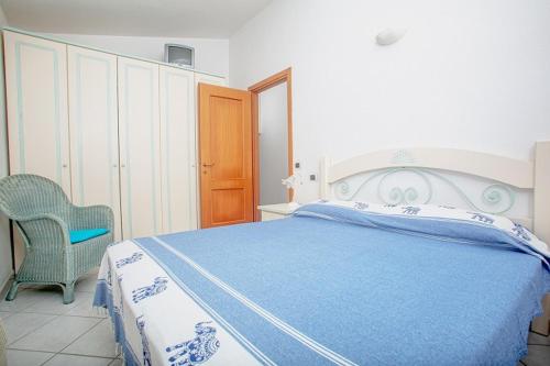 a bedroom with a blue and white bed and a chair at Casa Ginevra in Santa Teresa Gallura