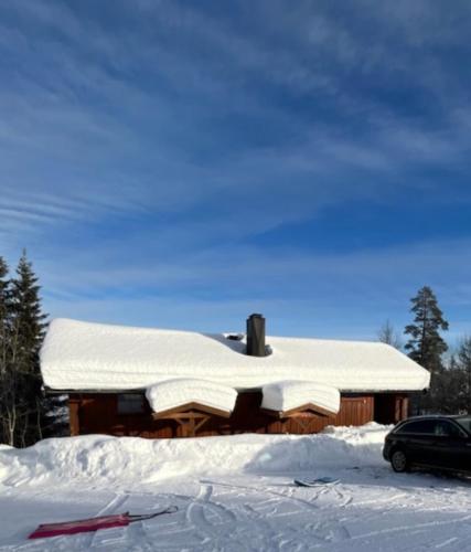 una cabaña cubierta de nieve con un coche aparcado en la nieve en Trysil - Ski in/out, en Trysil