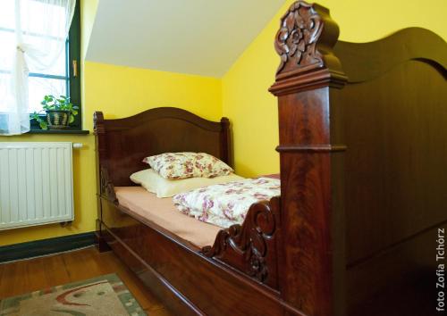 a bed with a wooden frame in a yellow room at Cyprianówka in Warszowice