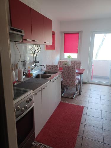 een keuken met witte kasten en een rood tapijt bij Apartment M&A in Osijek