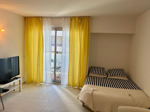 a bedroom with a bed and a tv and yellow curtains at ★★★ Paradis Prado Mermoz proximité Mer★★★ in Marseille