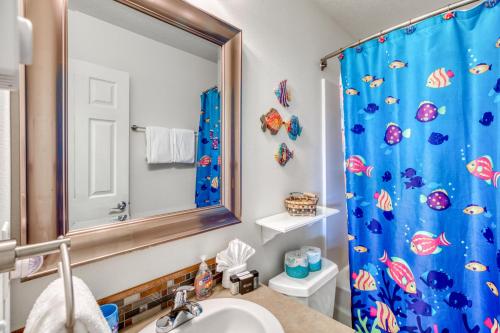 a bathroom with a blue shower curtain and a sink at Rockaway Retreat - Meredith Lodging in Rockaway Beach