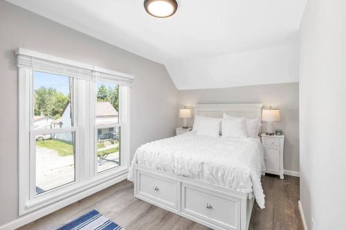 a white bedroom with a bed and a window at Pets, Big Groups Welcome: HotTub, Firepit, Grill in Bay City
