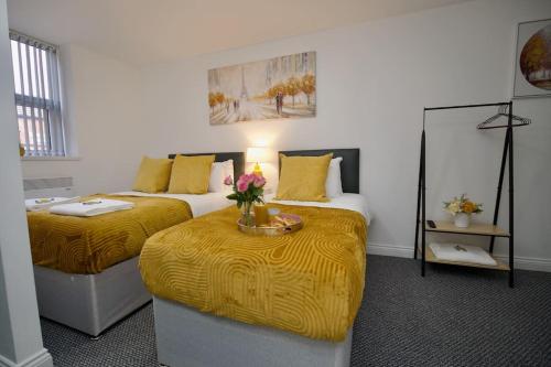 a bedroom with two beds and a table with flowers on it at Swan Studio Two - Coventry in Coventry