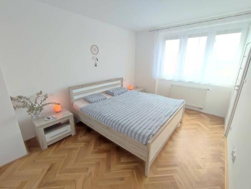 a white bedroom with a bed and a wooden floor at Apartmán Pod zámkem in Mikulov