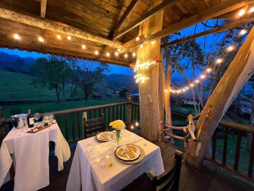 a dining room with two tables and lights on a porch at El Agrado Restaurante Cabañas in Líbano