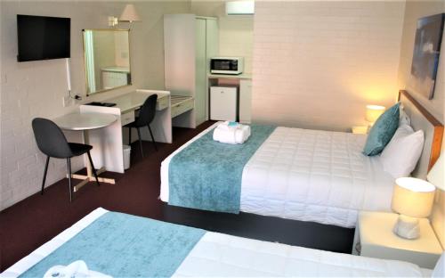 a hotel room with a bed and a desk and a kitchen at Club Motel Armidale in Armidale
