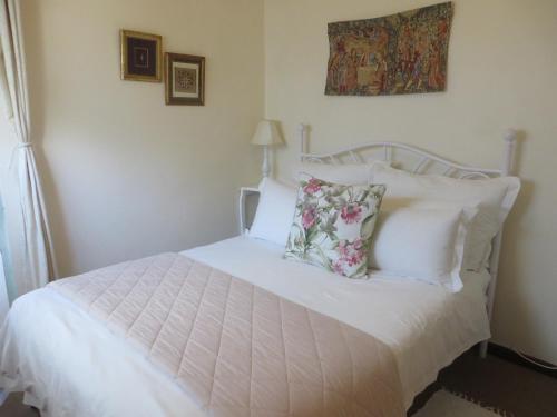 a bedroom with a bed with white sheets and pillows at Rose and Ale Self Catering Units in Gonubie