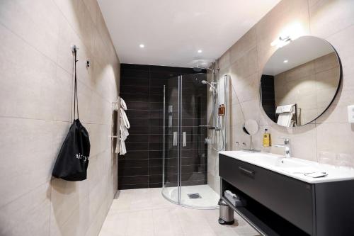 een badkamer met een douche, een wastafel en een spiegel bij Statt Hassleholm BW Signature Collection in Hässleholm