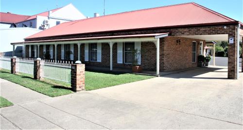 a brick building with a red roof and a fence at Club Motel Armidale in Armidale