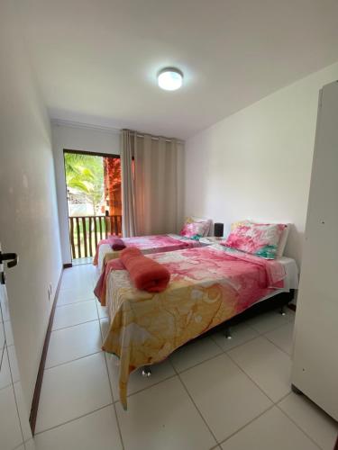 1 dormitorio con cama con sábanas rosas y ventana en Village Itacimirim, en Camaçari