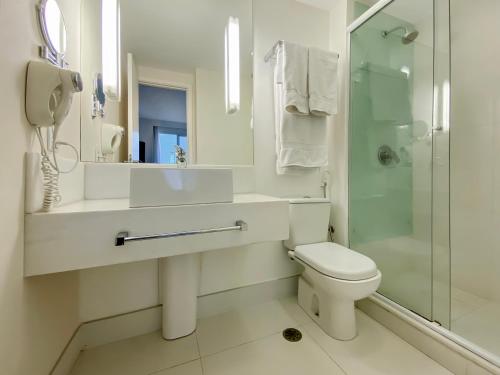 a white bathroom with a toilet and a shower at Sofisticado Hotel na Vila Olimpia in São Paulo