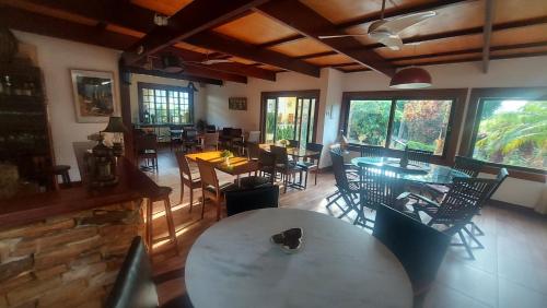 a dining room with tables and chairs and windows at 3 Palmeiras Guest Lounge in Miguel Pereira