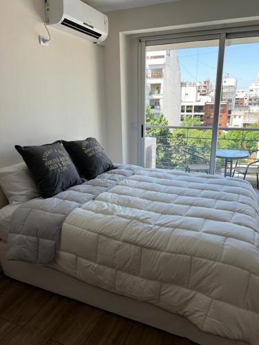 1 cama grande en un dormitorio con ventana grande en Glamoroso departamento de 1 ambiente en belgrano en Buenos Aires