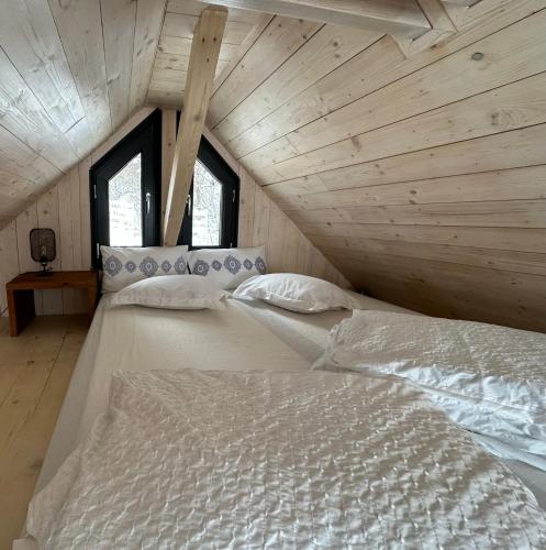 two beds in a room with wooden walls and windows at Bramble Tiny House in Zărneşti