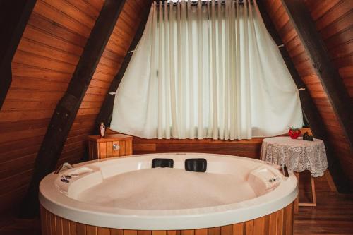 een groot bad in een kamer met een raam bij Chalé romântico com banheira de hidromassagem e lareira in Bom Retiro