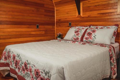 een bed in een kamer met houten wanden bij Chalé romântico com banheira de hidromassagem e lareira in Bom Retiro