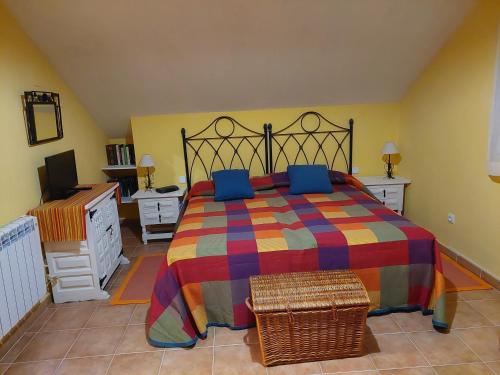 - une chambre avec un grand lit et une couverture colorée dans l'établissement Disfrutar y relajarse en el Robledal, à Zarzuela del Monte