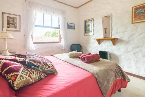 Un dormitorio con una cama rosa con almohadas y una ventana en La Vie en Rose, en Campos do Jordão