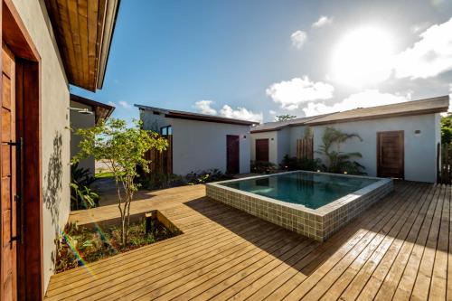 a backyard with a swimming pool and a wooden deck at Vila Gema Maraú in Marau