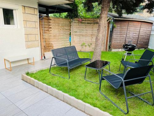 tre sedie e un tavolo e un albero in un cortile di Superbe studio avec entrée et jardin privés à moins de 15 minutes de Paris a Bagneux