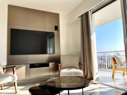 ein Wohnzimmer mit einem TV, einem Tisch und Stühlen in der Unterkunft Appartement bord de mer avec piscine in Saint-Laurent-du-Var