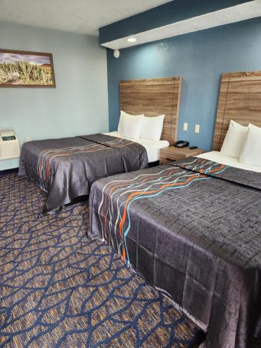 a hotel room with two beds and blue walls at Travelodge by Wyndham Barstow in Barstow