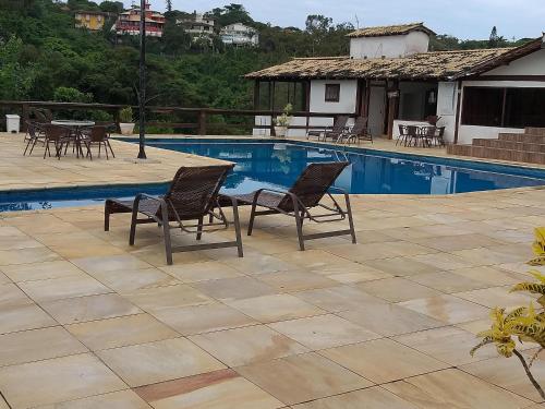einen Pool mit Stühlen, einem Tisch und einem Haus in der Unterkunft Casa Agradavel Buzios - in Búzios
