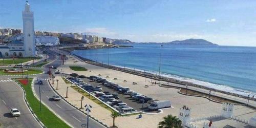 a beach with a lot of cars parked next to the water at Beau et propre Appartement de FAMILLE dans un immeuble calme et FAMILIALE à Bab Sebta in Fnidek