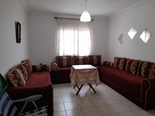 a living room with a couch and a table at Beau et propre Appartement de FAMILLE dans un immeuble calme et FAMILIALE à Bab Sebta in Fnidek
