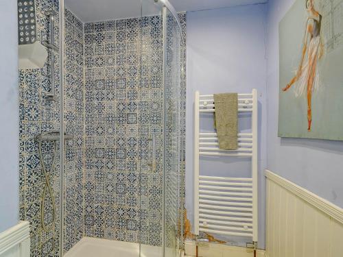 a bathroom with a shower with blue and white tiles at Meadow House Apartment in Moffat