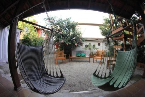 3 hamacas colgadas en un patio con una mesa en Amares Hostel, en Florianópolis