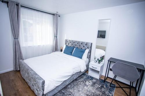 um quarto com uma cama com almofadas azuis e uma secretária em la vida in casa em Thamesmead