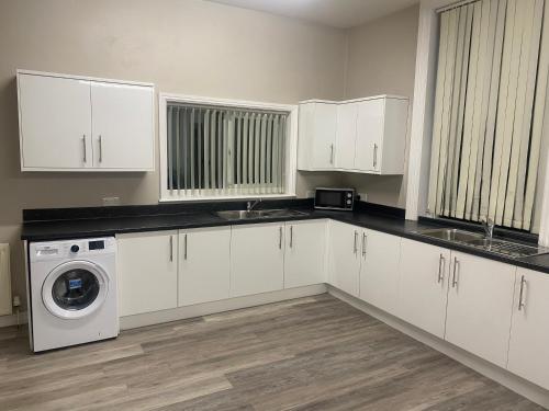 a kitchen with white cabinets and a washer and dryer at SEV House, Wakefield City Center in Wakefield