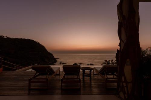 a group of chairs and a table on a deck with the ocean at Casa Roni by Xeno - 5 Bedroom Luxury Villa with Ocean View in Playa Estacahuite