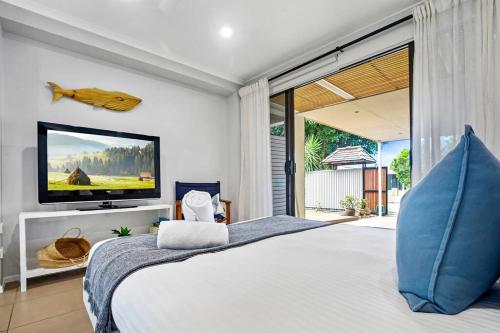 a bedroom with a large bed with a tv on the wall at Charming Coastal Studio 900m to the Beach in Kawana Waters