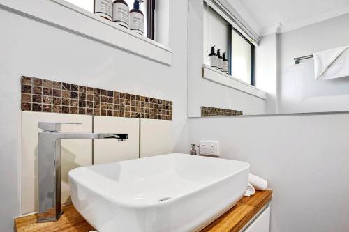 a white bathroom with a sink and a mirror at Charming Coastal Studio 900m to the Beach in Kawana Waters